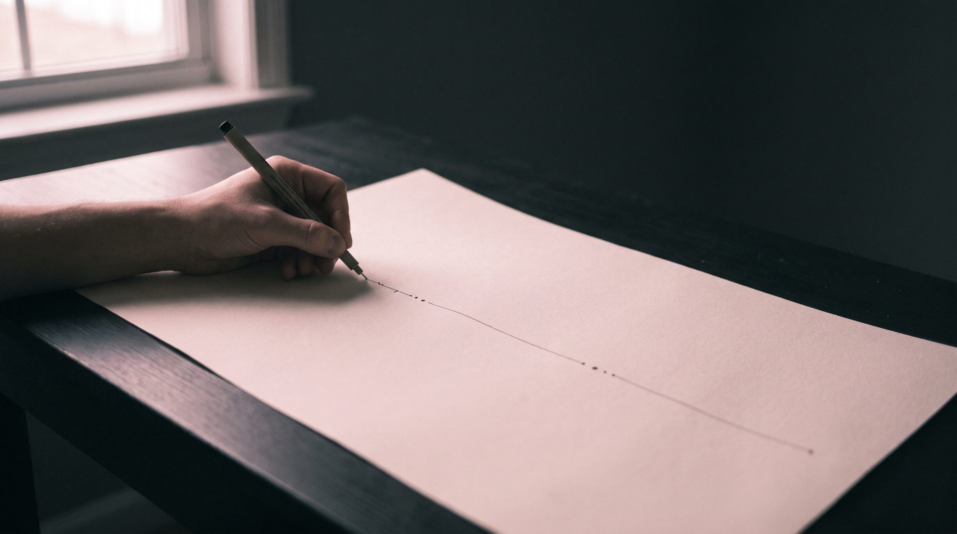 Hand zeichnet mit Bleistift eine Linie auf Papier